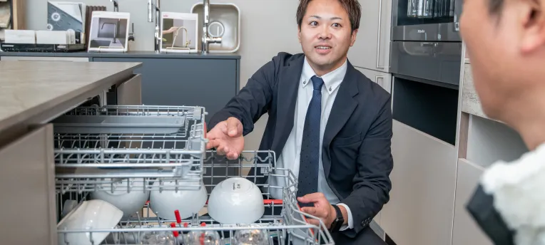 食洗機の中を見せるスタッフの写真