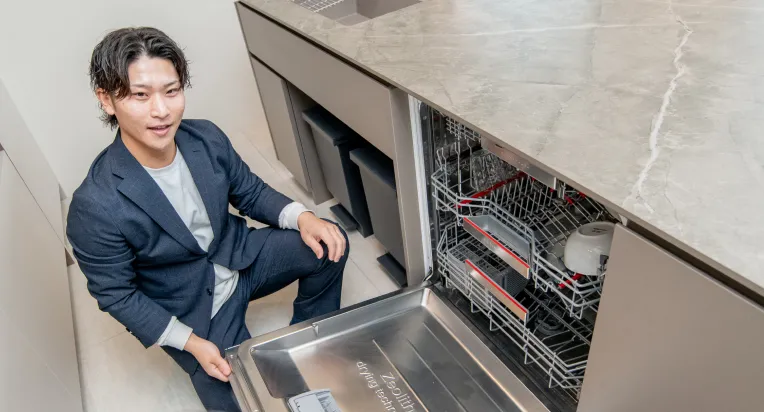 食洗機の中を見せるスタッフの写真
