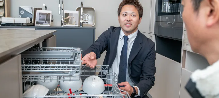 食洗機の中を見せるスタッフの写真