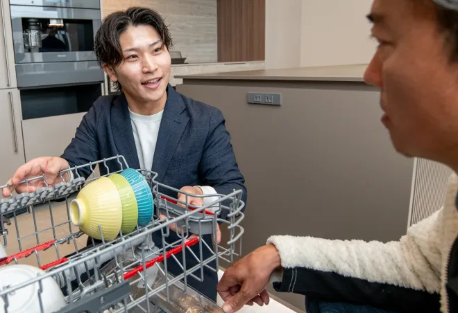 食洗機の中を見せるスタッフの写真